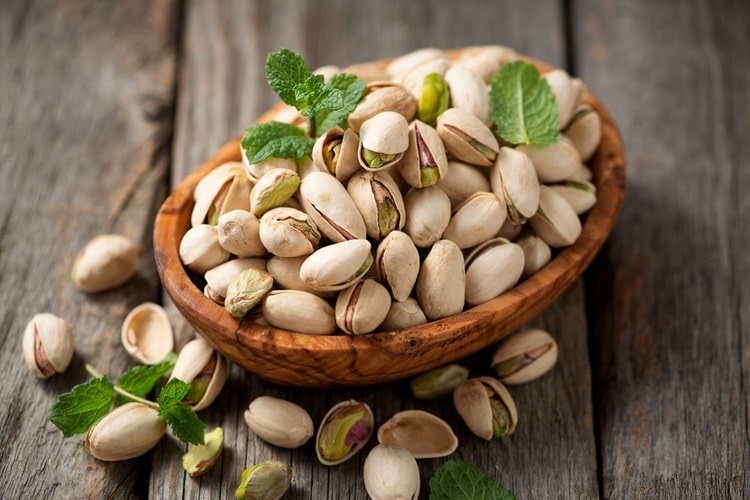 Bowl of pistachios on a wooden surface